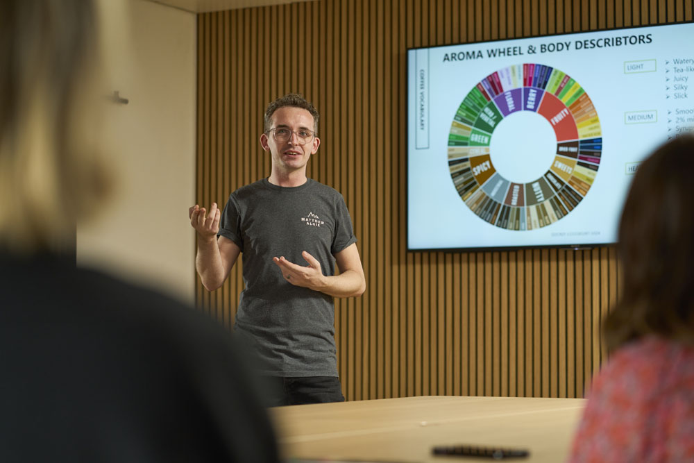 Barista trainer, Colin, with grey Matthew Algie branded t-shirt presenting to a coffee school.