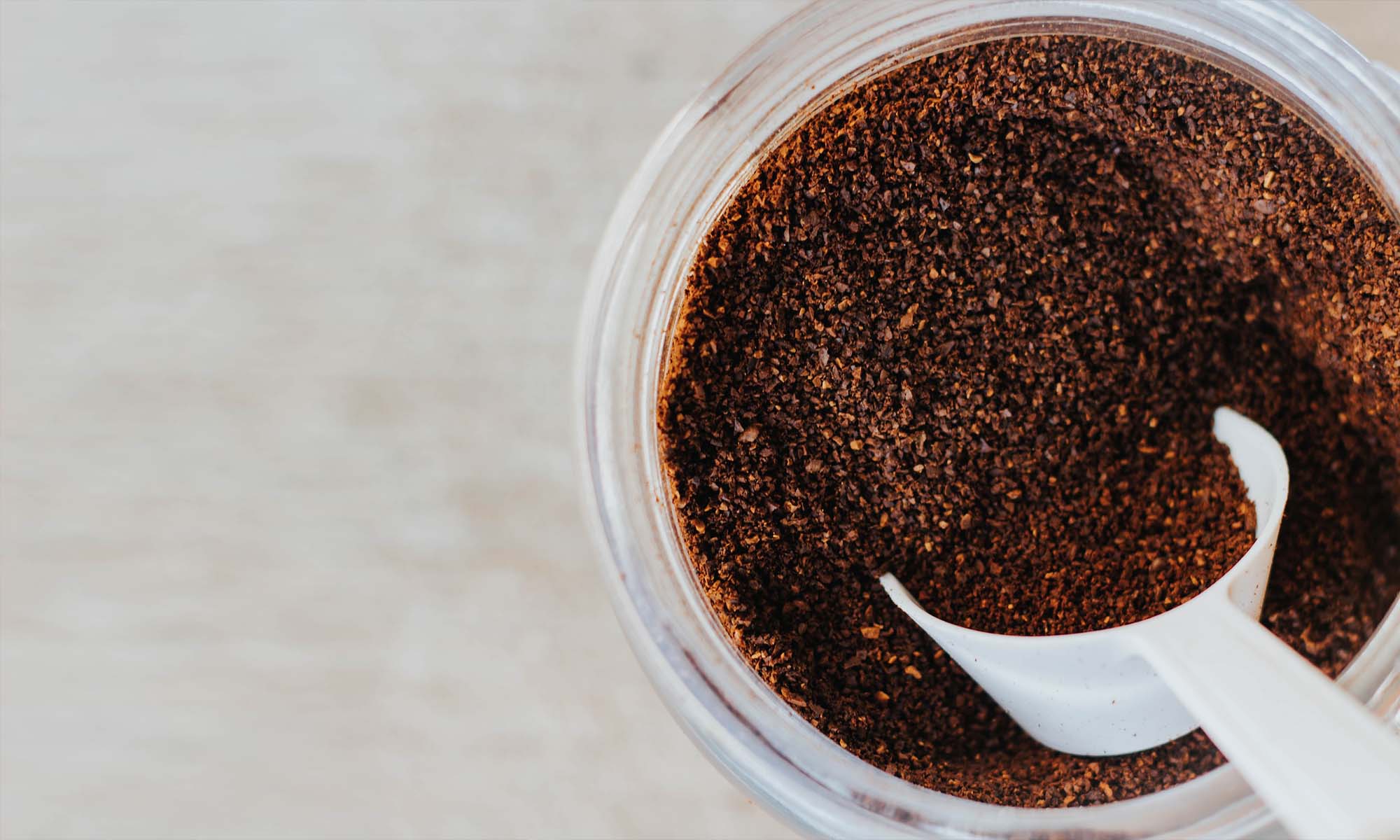 Jar of ground coffee with a plastic scoop