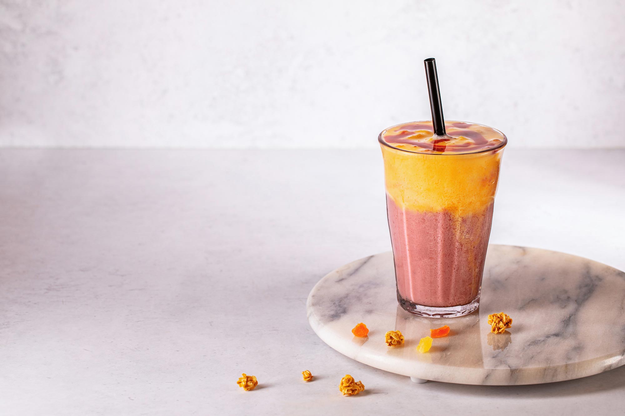 Peach Melba drink with straw on a marble presentation tray.